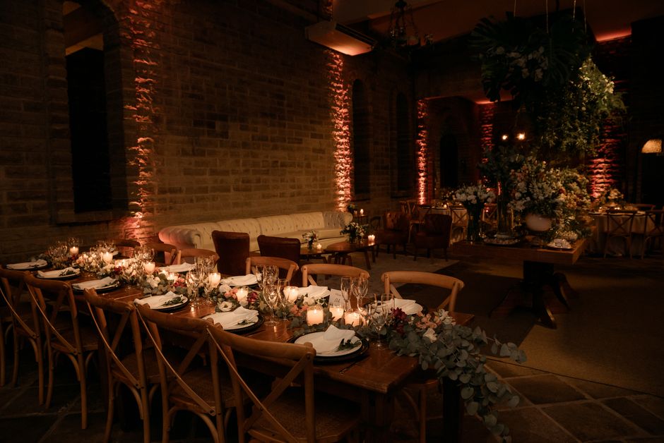 A long table set for dinner in a brick-walled room