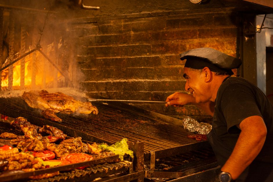 A cook tending food over an open fire in a brick kitchen